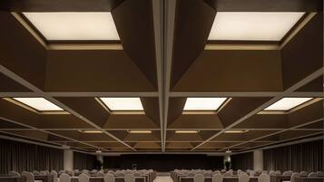 A conference room with a symmetrical layout, multiple tables, and chairs arranged for meetings.