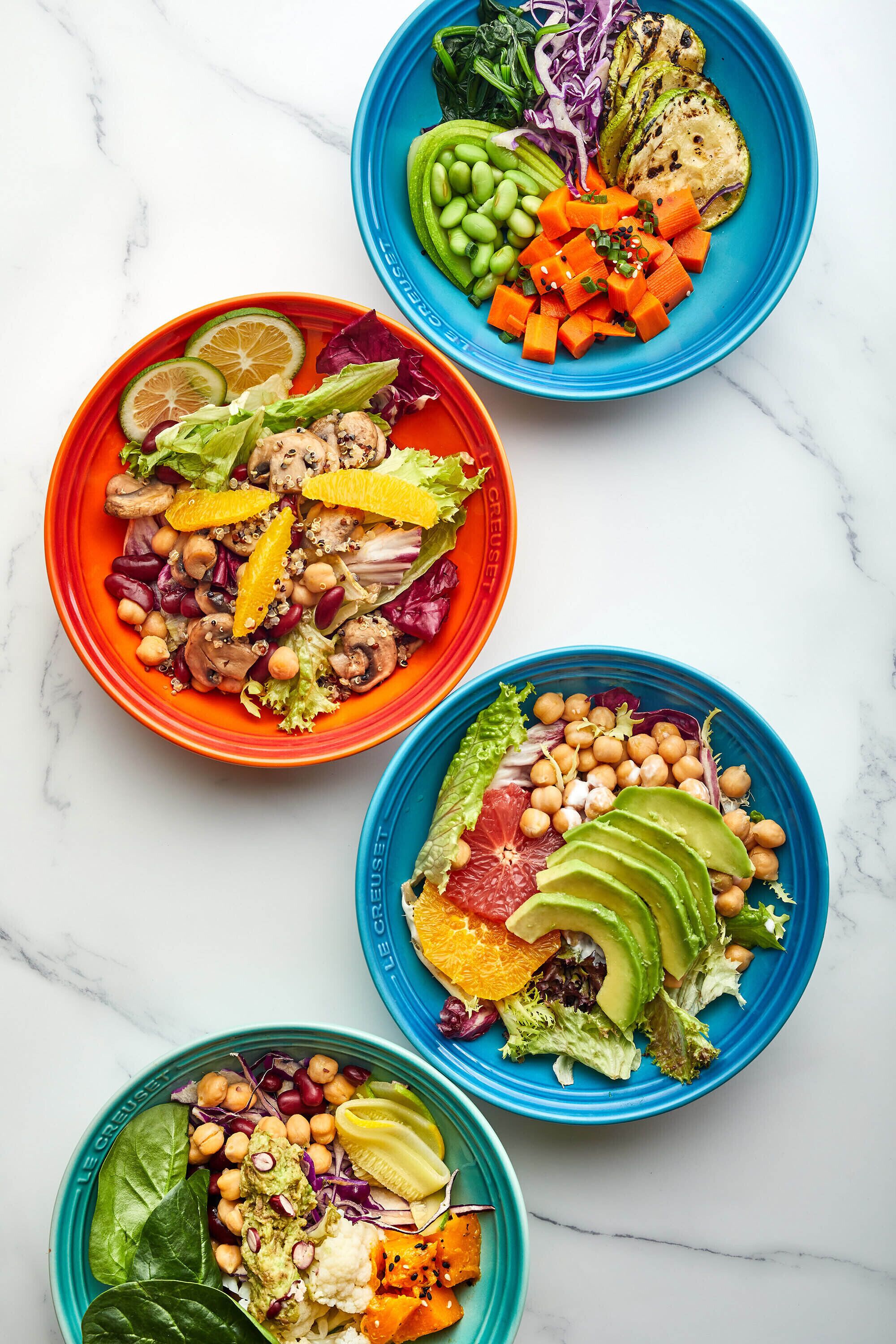 Tres ensaladas coloridas con diferentes verduras y garbanzos.