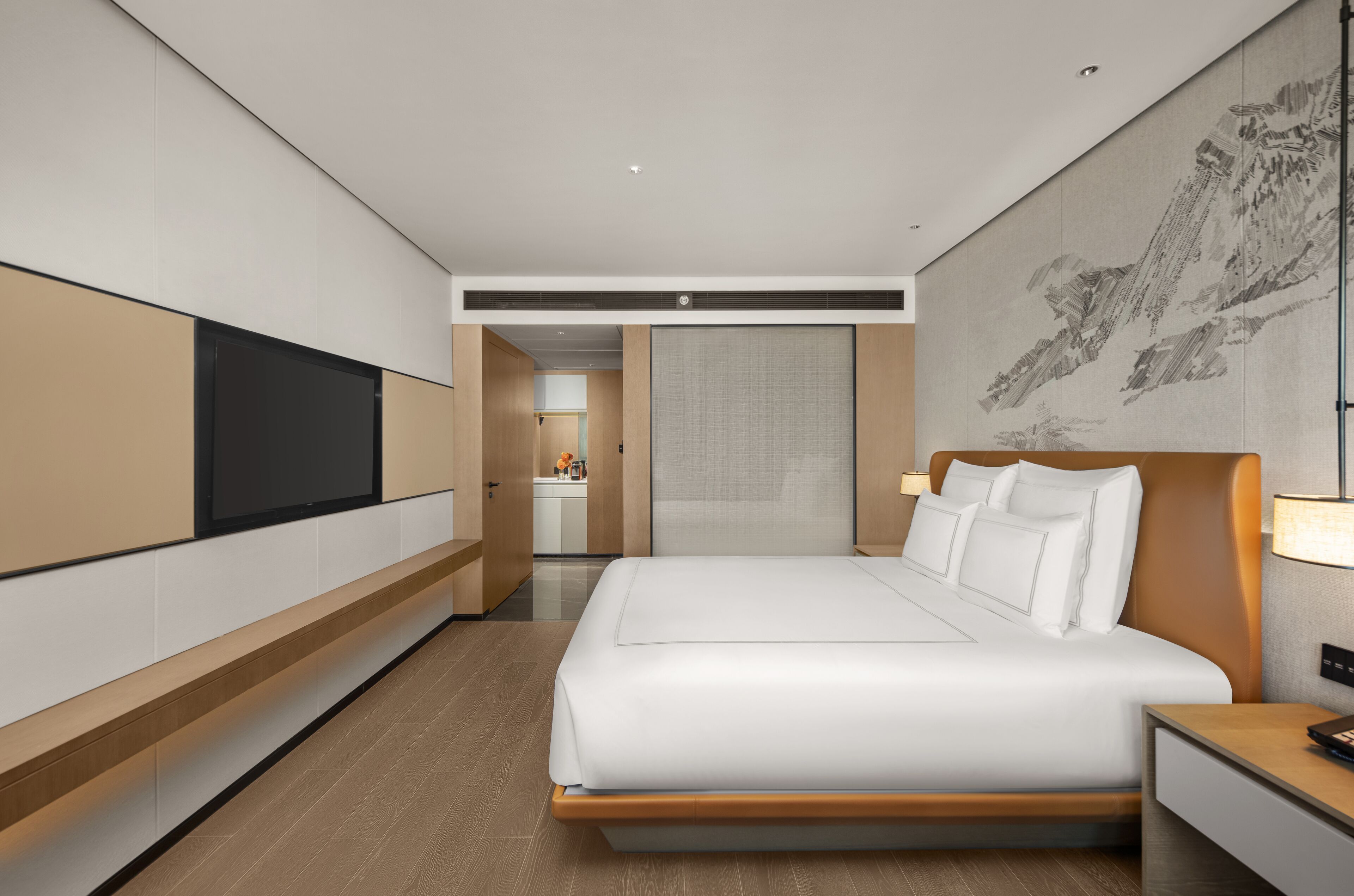 Habitación de hotel moderna con una cama grande, un televisor de pantalla plana montado en la pared, una mesita de noche y una obra de arte de gran tamaño en la pared.