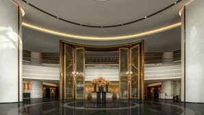 Un hall d’entrée spacieux agrémenté d’une composition florale centrale, doté d’un plafond incurvé et d’un design moderne.