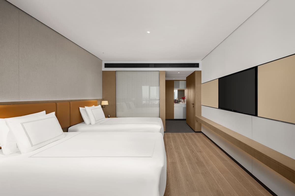 Ein Hotelzimmer mit zwei Betten, einem Fernseher und einer Küchenzeile.