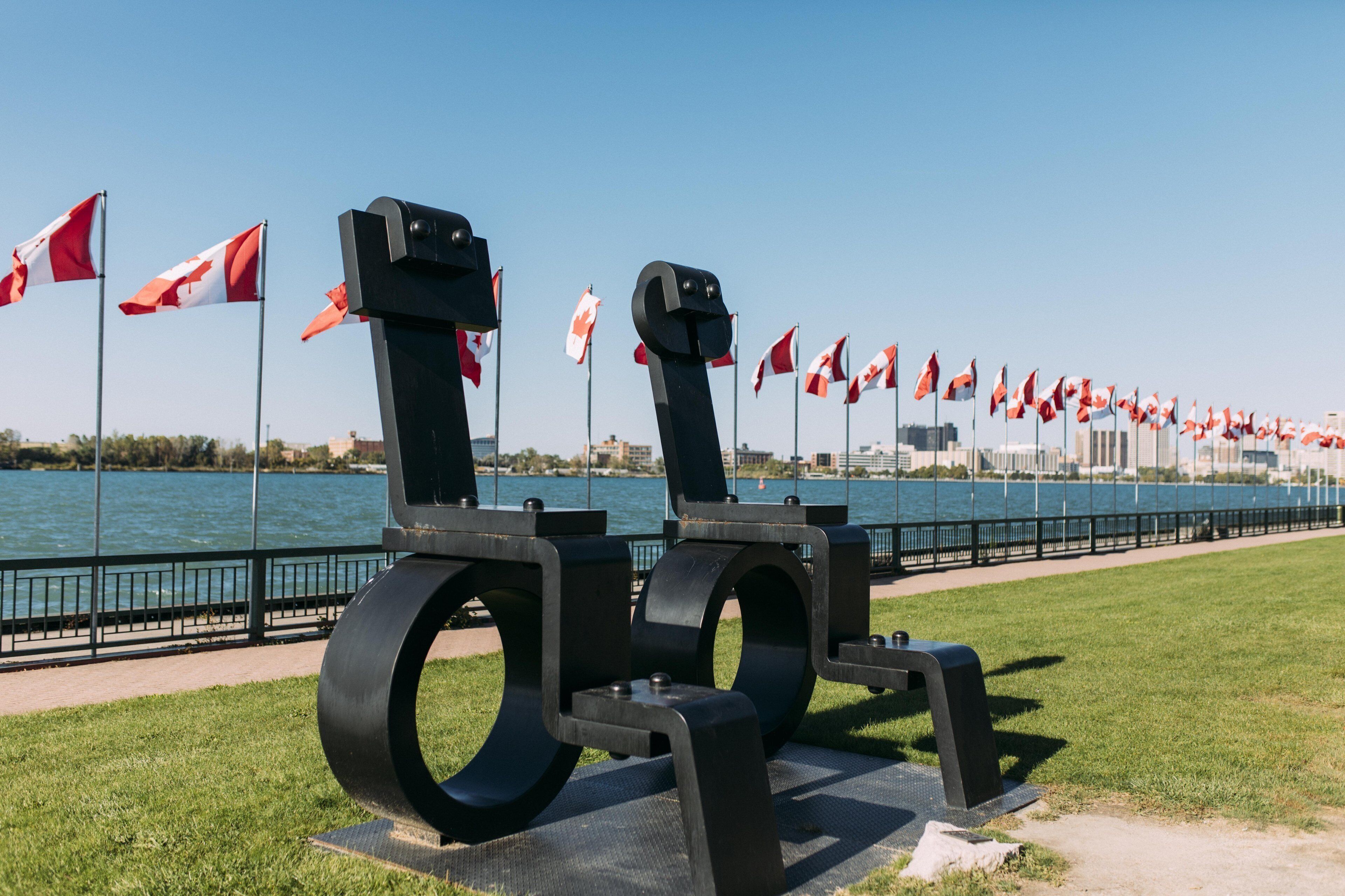 A sculpture with a water view, a grassy area, and flags.