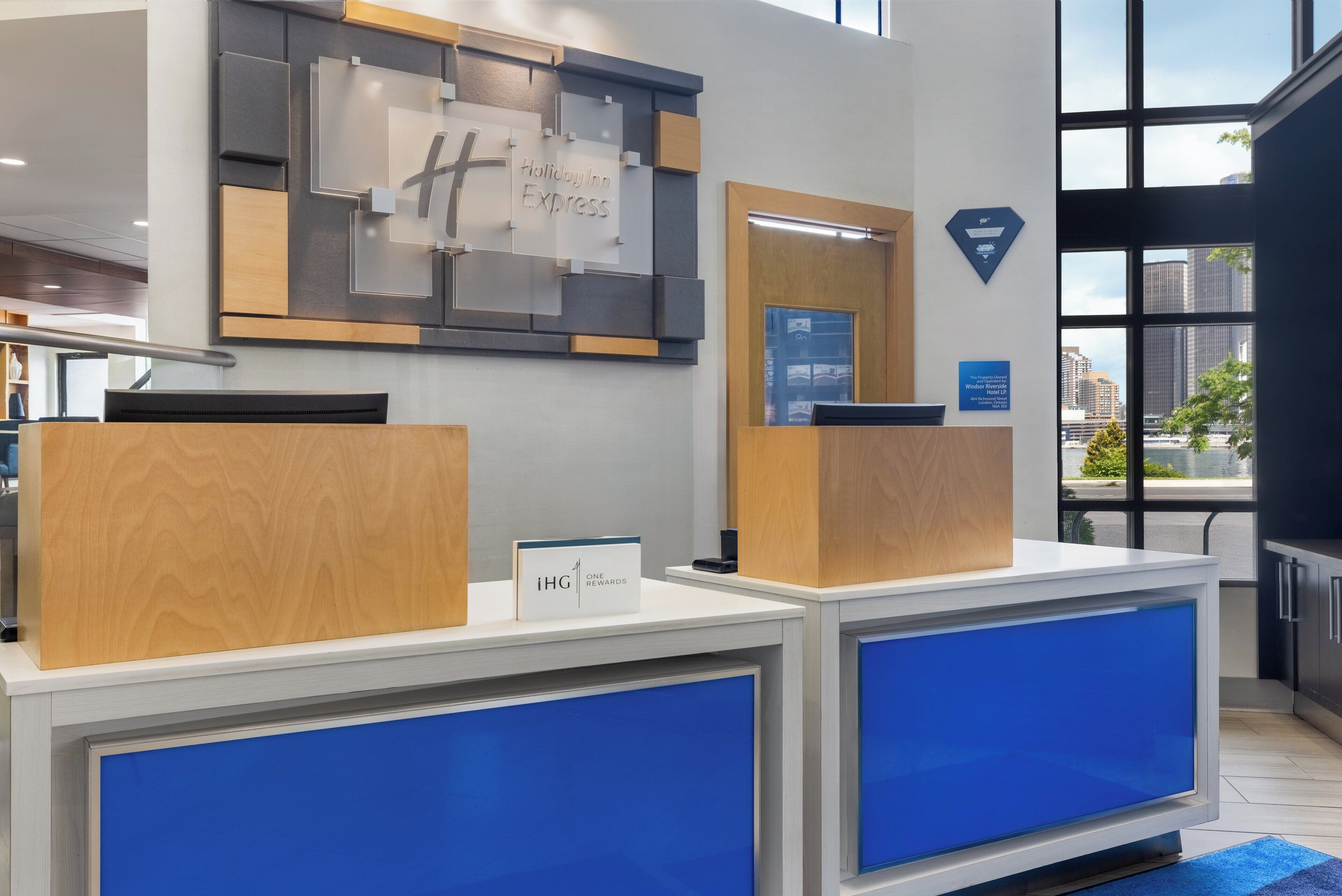 Un comptoir d’accueil d’hôtel au design moderne, une enseigne « Holiday Inn Express » et une vue sur la ville à travers de grandes fenêtres.