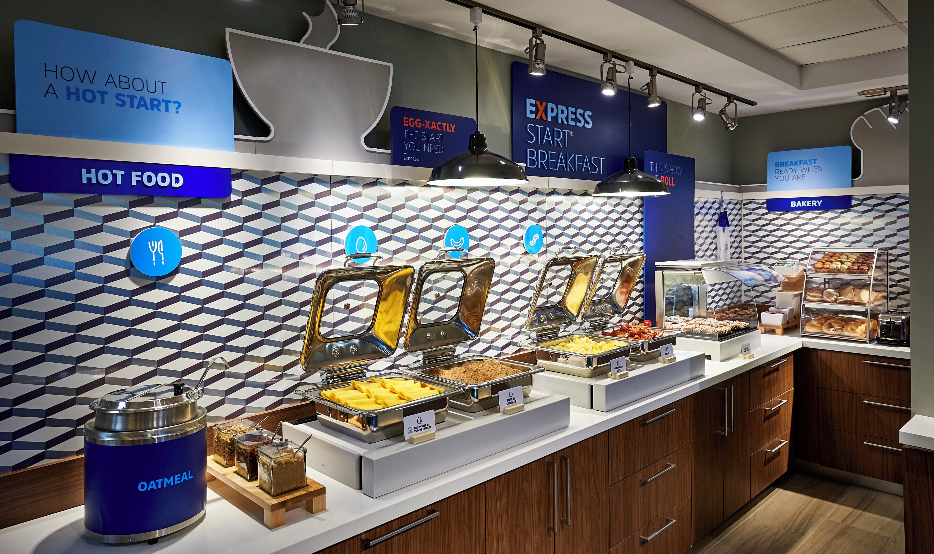 A breakfast buffet with labeled food stations including oatmeal, turkey sausage, and other hot foods.