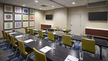 A conference room with multiple tables and chairs, framed artwork on the walls, and a door with a closed panel.