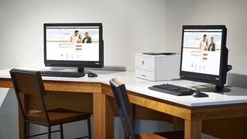 A modern office setup with two monitors, a printer, and a wooden desk.