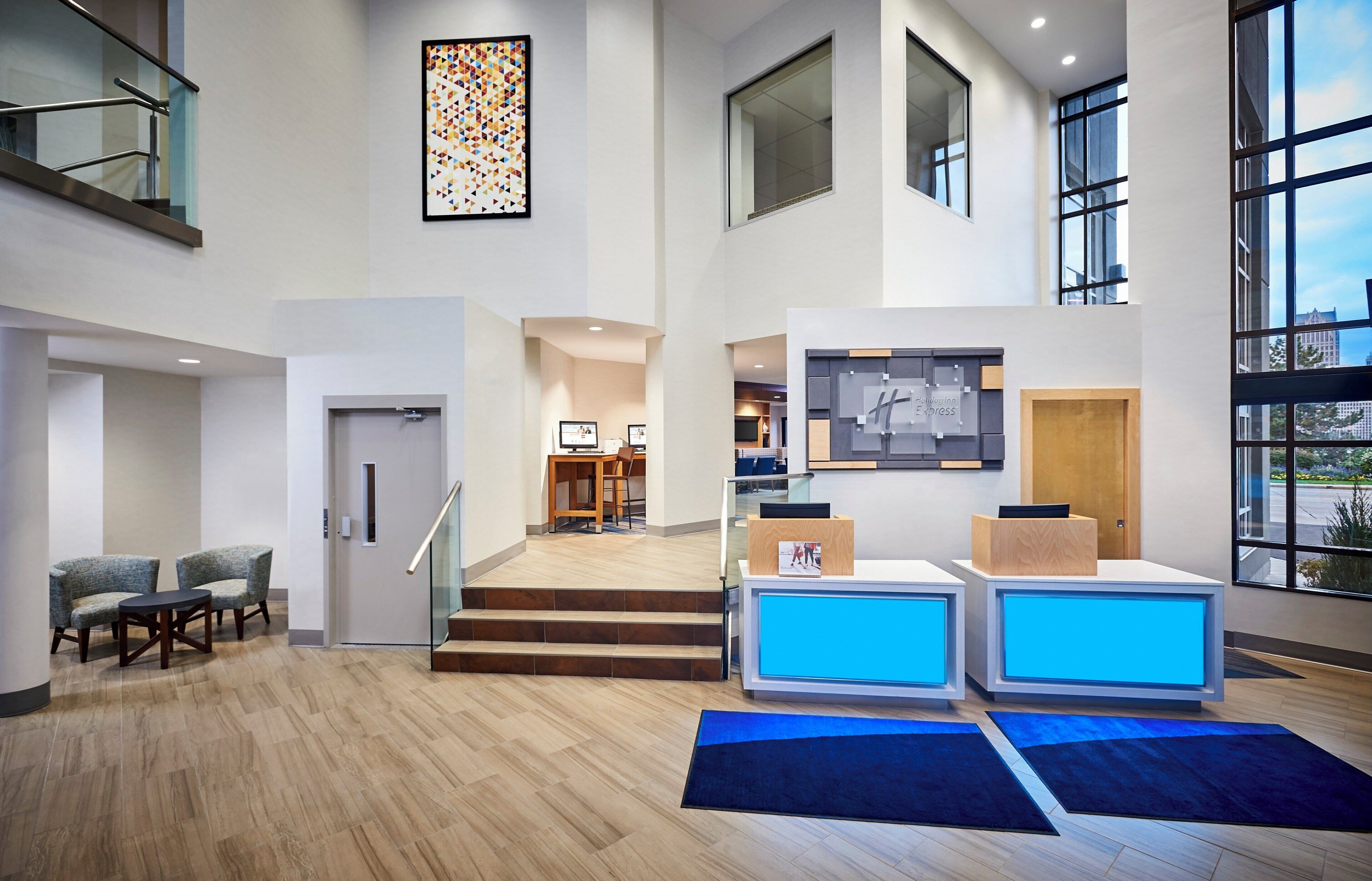 A spacious lobby with a reception desk, seating area, and a staircase leading to upper floors.