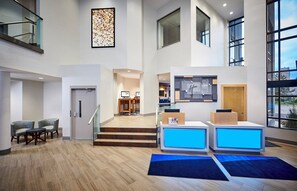 A spacious lobby with a reception desk, seating area, and a staircase leading to upper floors. - Holiday Inn Express Windsor Waterfront by IHG (Windsor)