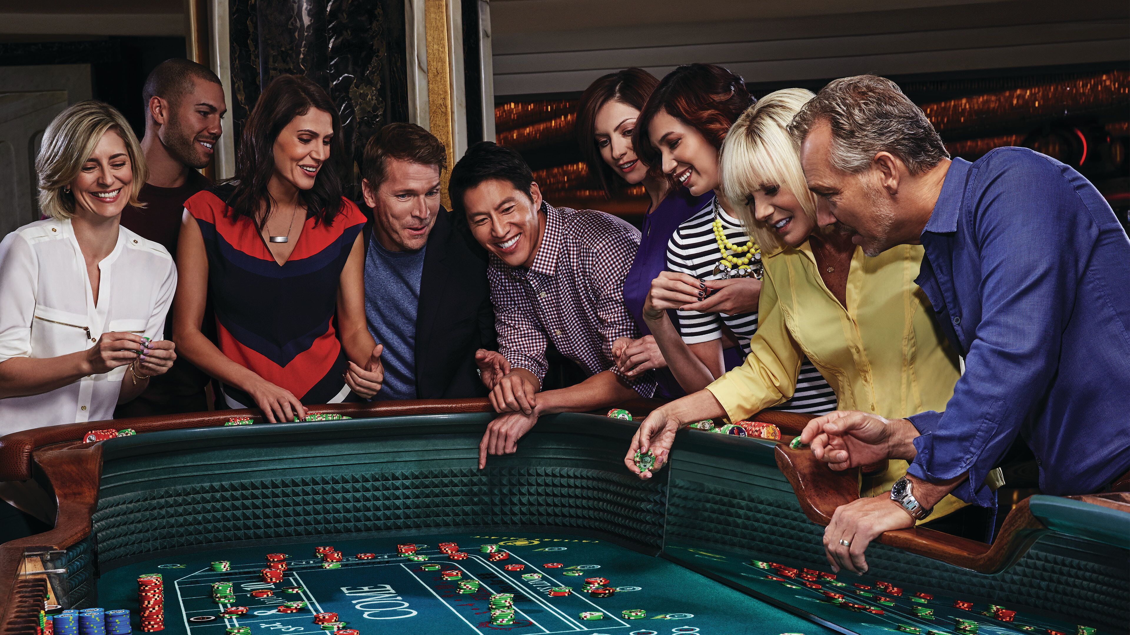 A group of people gathered around a casino table with chips and cards.