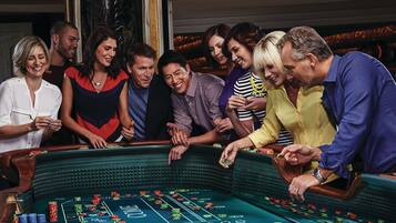 A group of people gathered around a casino table with chips and cards.