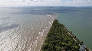 An aerial view of a coastal area with a beach, dense forest, and a clear sky. - Holiday Inn Express Windsor Waterfront by IHG (Windsor)