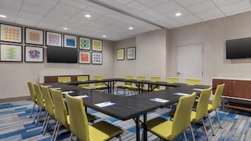 A conference room with a long table, yellow chairs, and framed artwork on the walls.