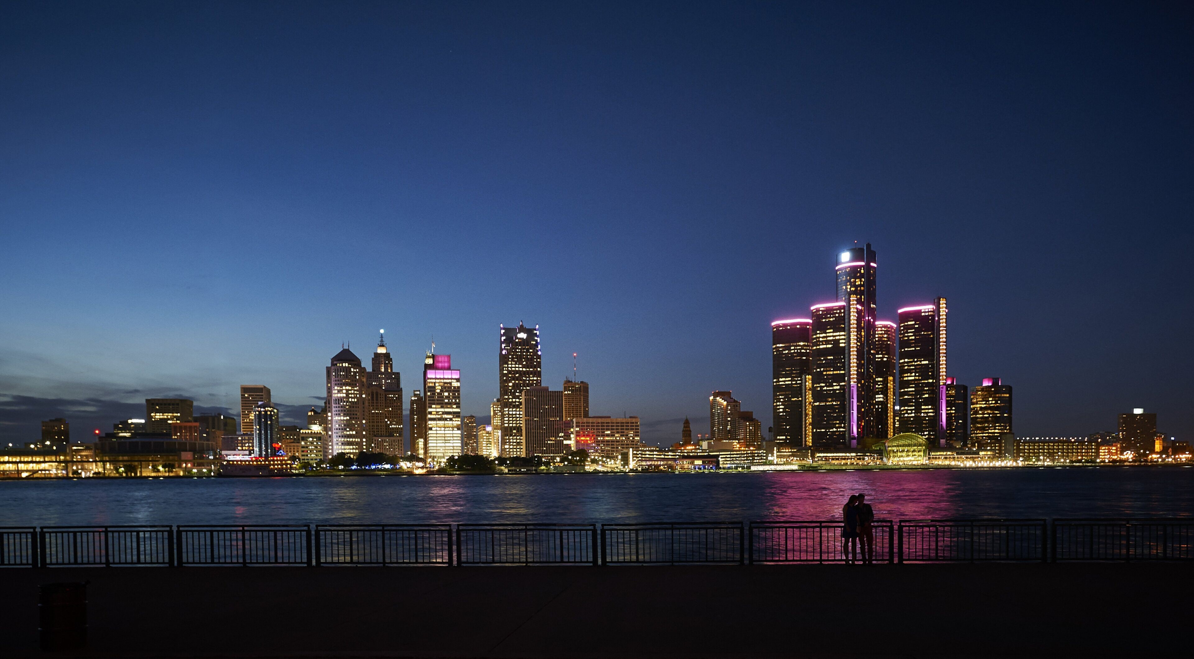 Un horizonte urbano nocturno con edificios iluminados a lo largo de una ribera.