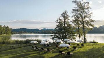 Un cadre agréable au bord du lac, avec des chaises et des parasols disposés pour créer un espace de détente en plein air.