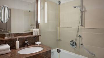A modern bathroom with a granite countertop sink, a large mirror, and a glass-enclosed shower area.