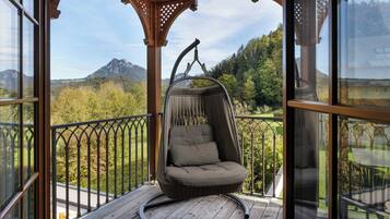 Une terrasse en bois avec un fauteuil suspendu donnant sur un paysage montagneux.