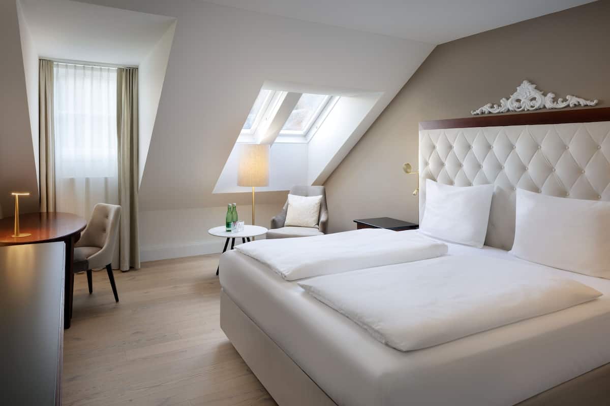 Une chambre d’hôtel avec un grand lit, un bureau, une chaise et une petite table.