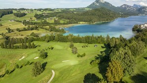 A golf course with a lake and mountains in the background.