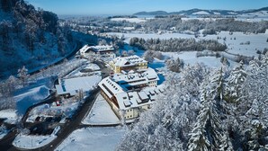 A snow-covered hotel with multiple buildings, a parking area, and a view of the surrounding snowy landscape.