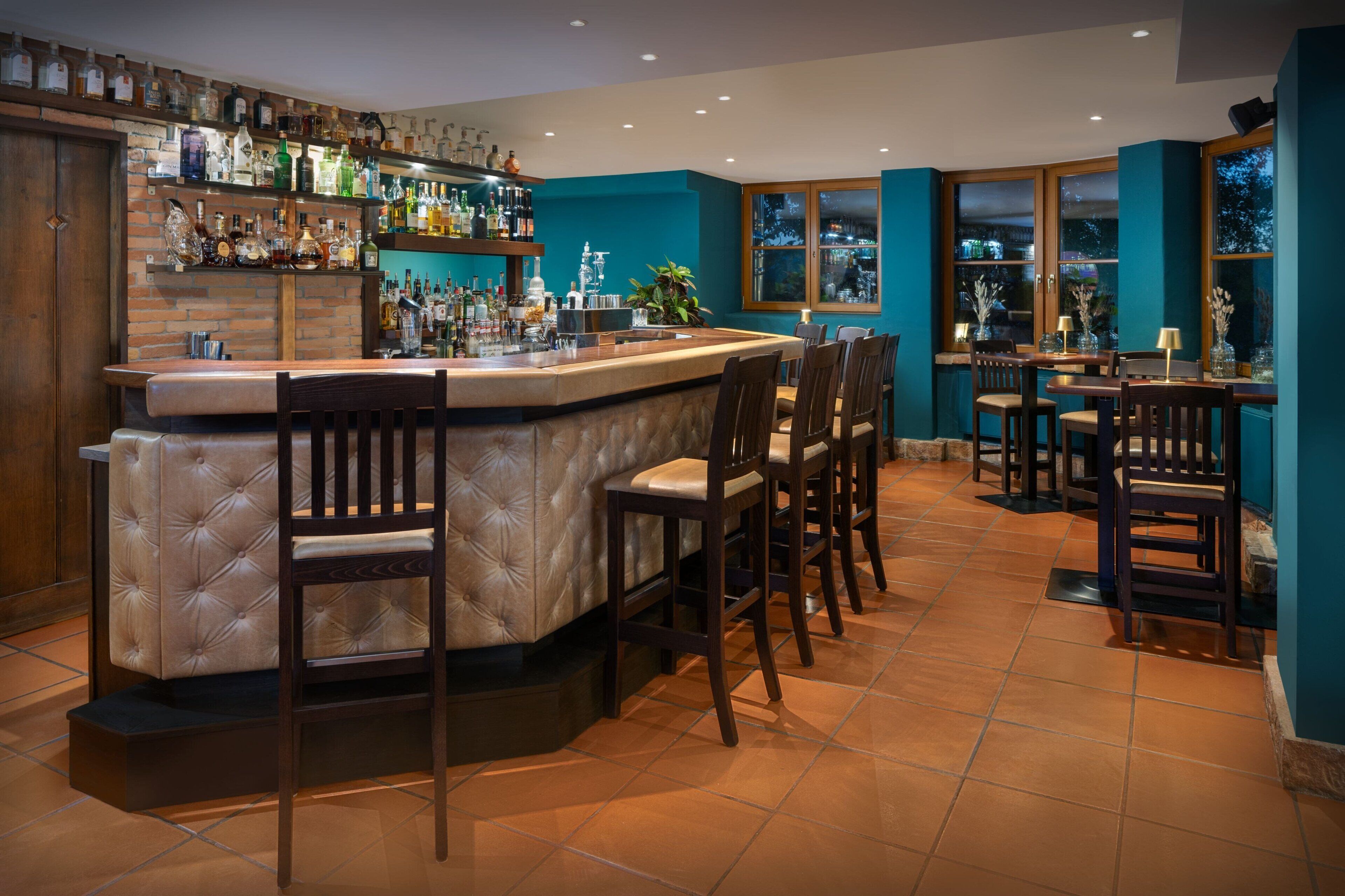A bar area with a counter, bar stools, and a variety of bottles.