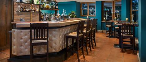 A bar area with a counter, bar stools, and a variety of bottles.