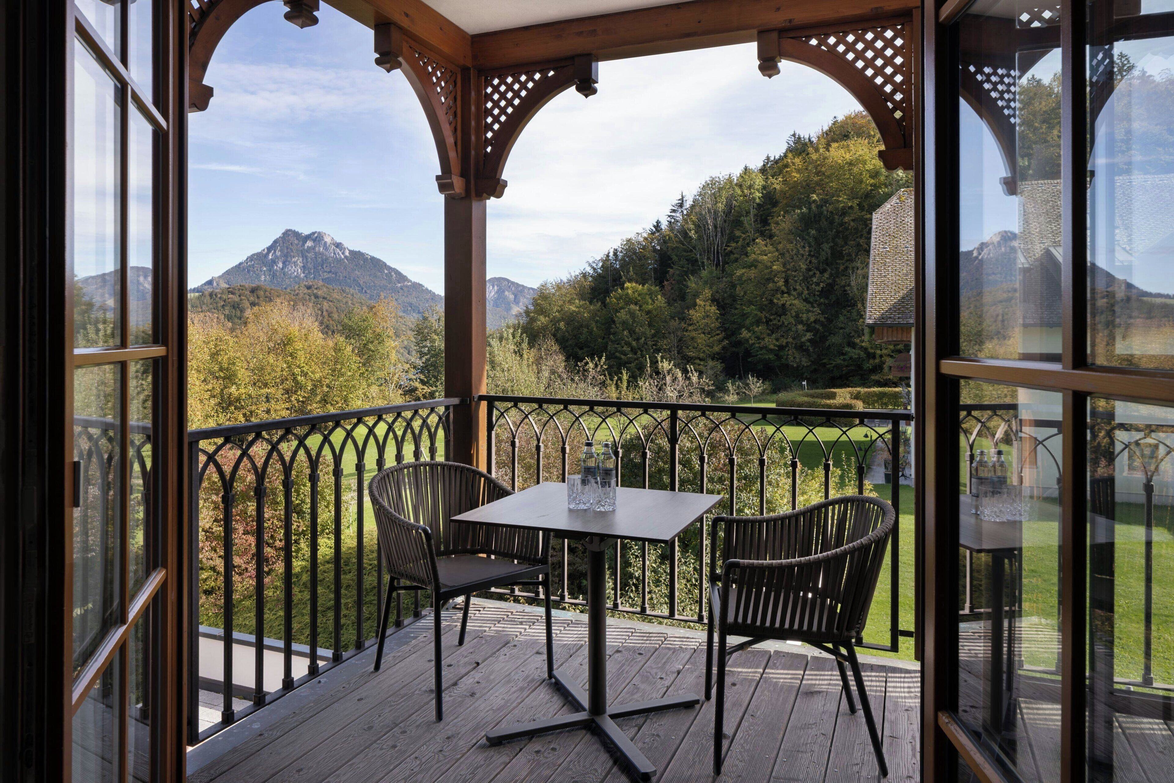 A covered outdoor area with a table and chairs, overlooking a mountainous landscape.