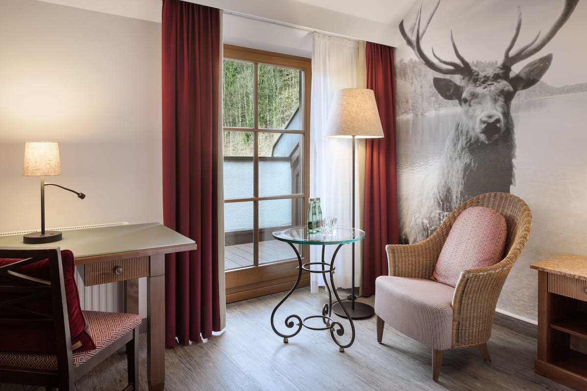 Une pièce comprenant une table à manger, une chaise, une lampe, un fauteuil en osier et une table en verre.