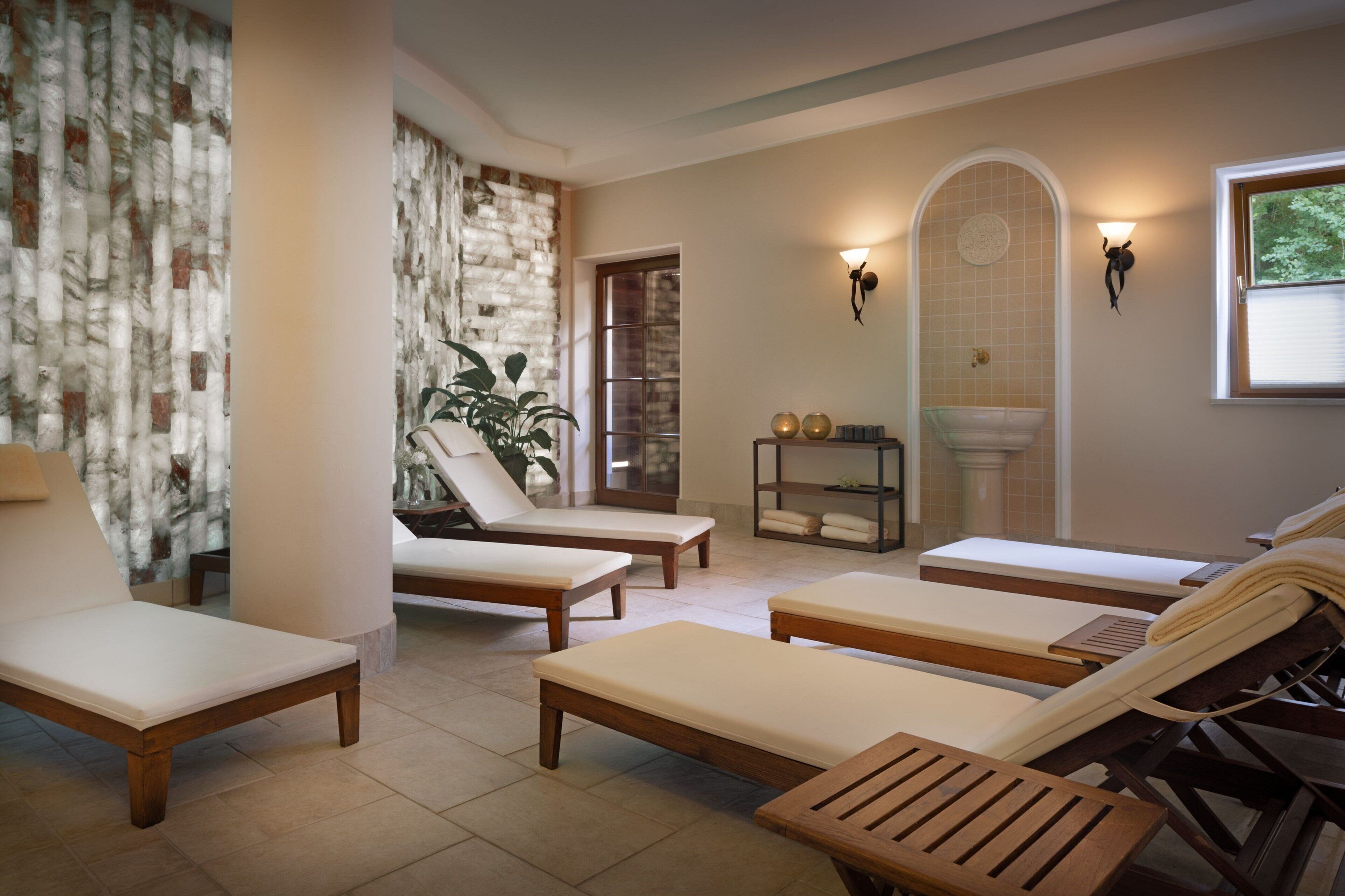 A spa area with multiple sun loungers, a small shelf with towels, and a wall-mounted light fixture.
