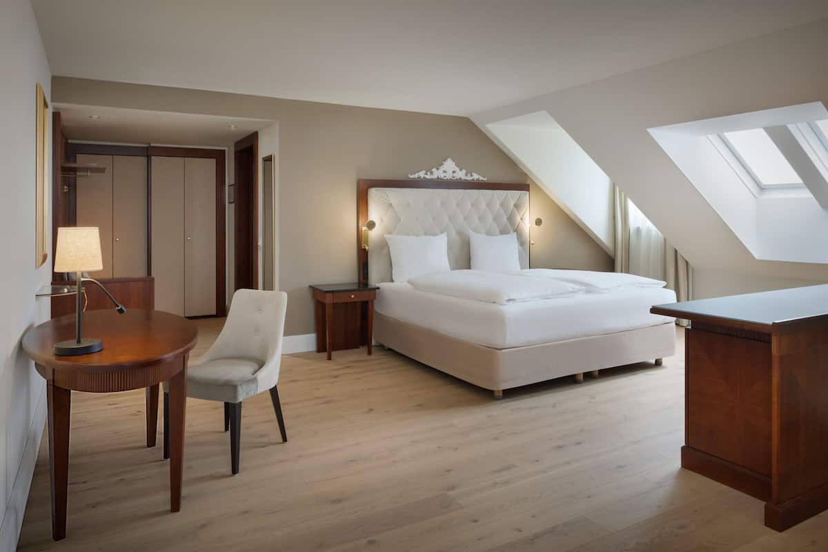 Une chambre à coucher avec un grand lit, un bureau, une chaise et une lampe.