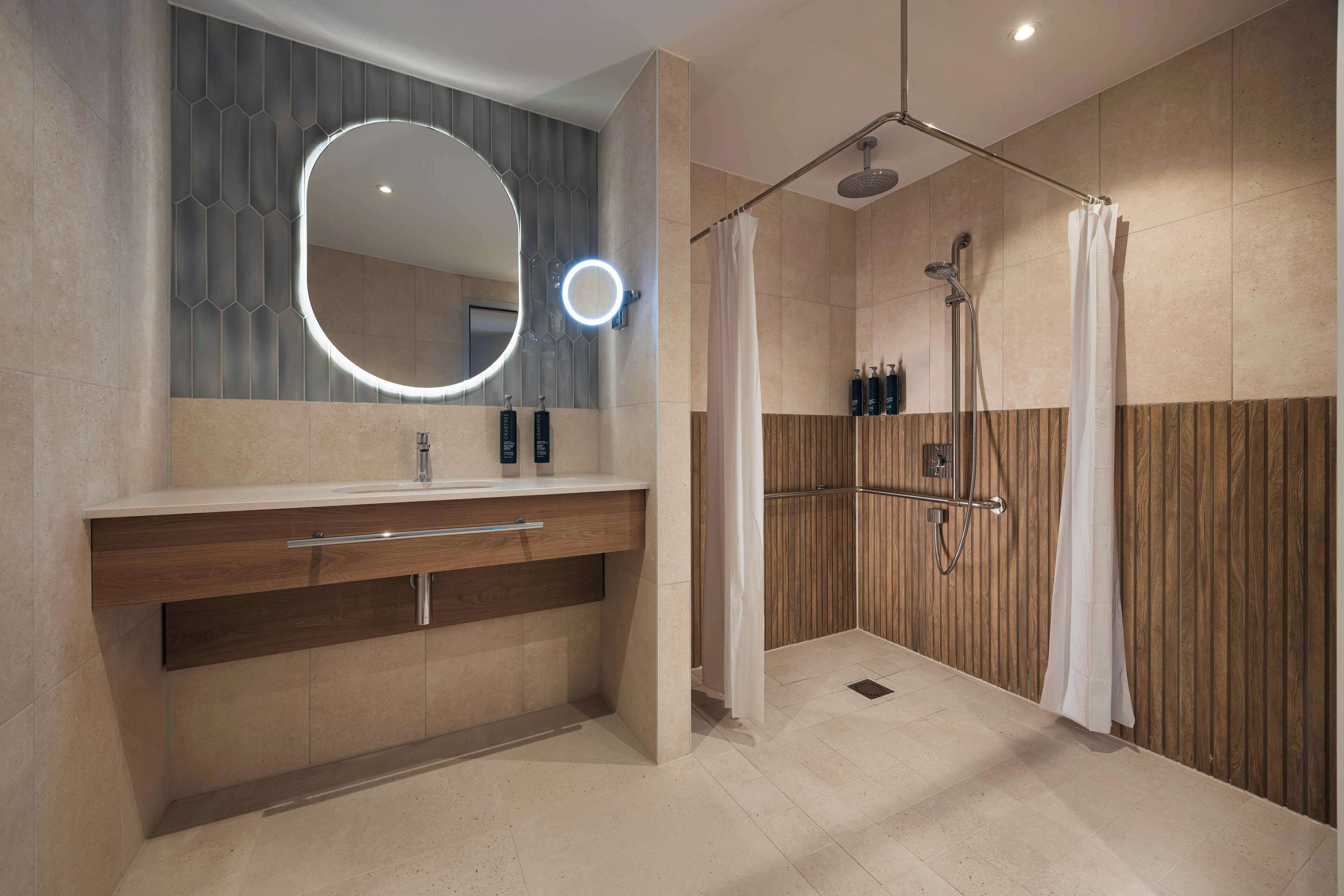 Un baño moderno con tocador, espejo, ducha y paneles de madera.