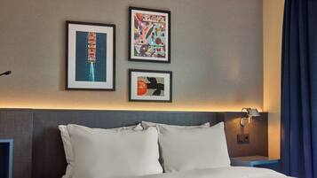 Een hotelkamer met een bed, een nachtkastje en drie ingelijste kunstwerken aan de muur.