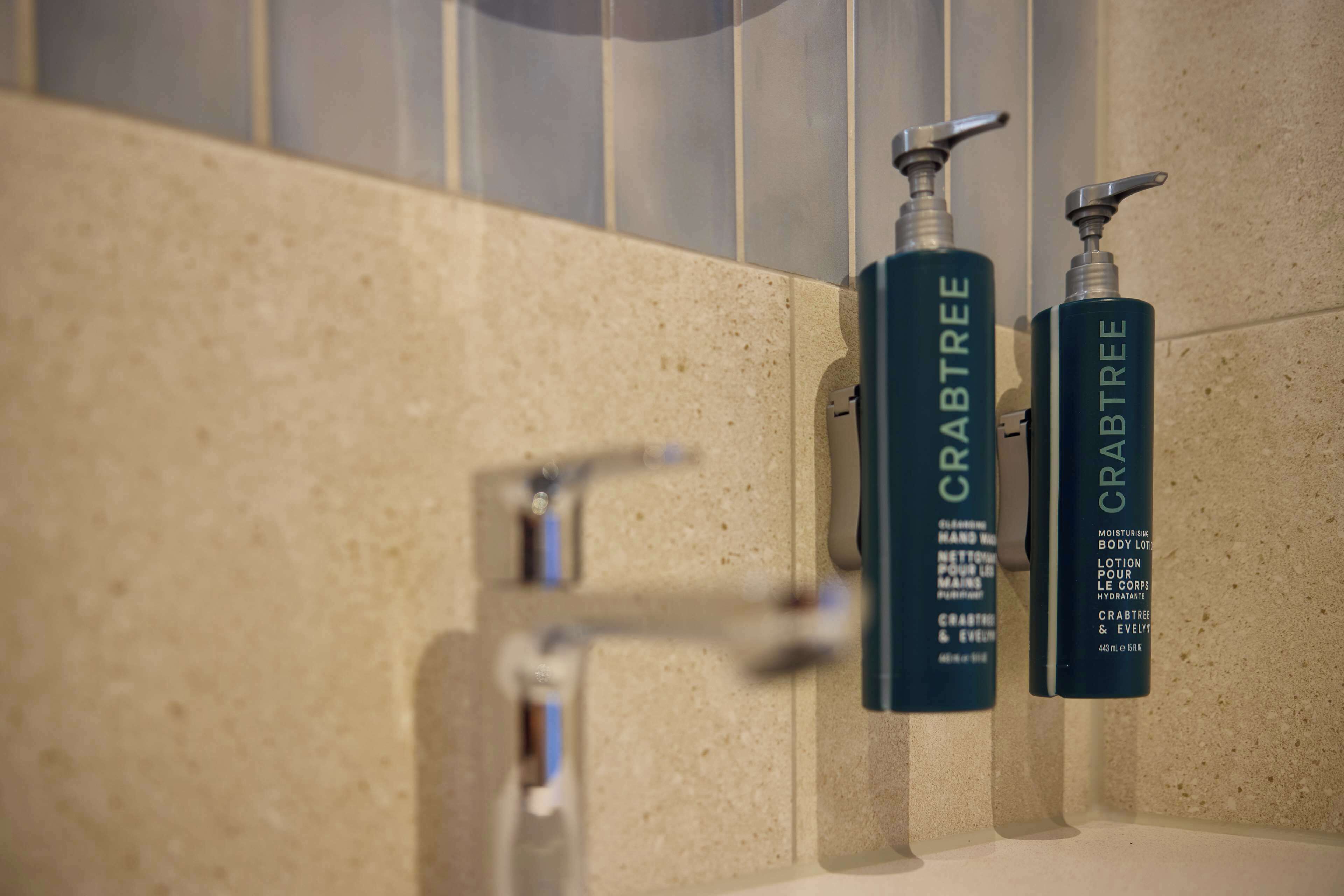 Two bottles of Crabtree body lotion on a bathroom counter.