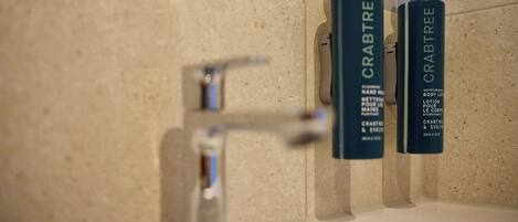 Two bottles of Crabtree body lotion on a bathroom counter.