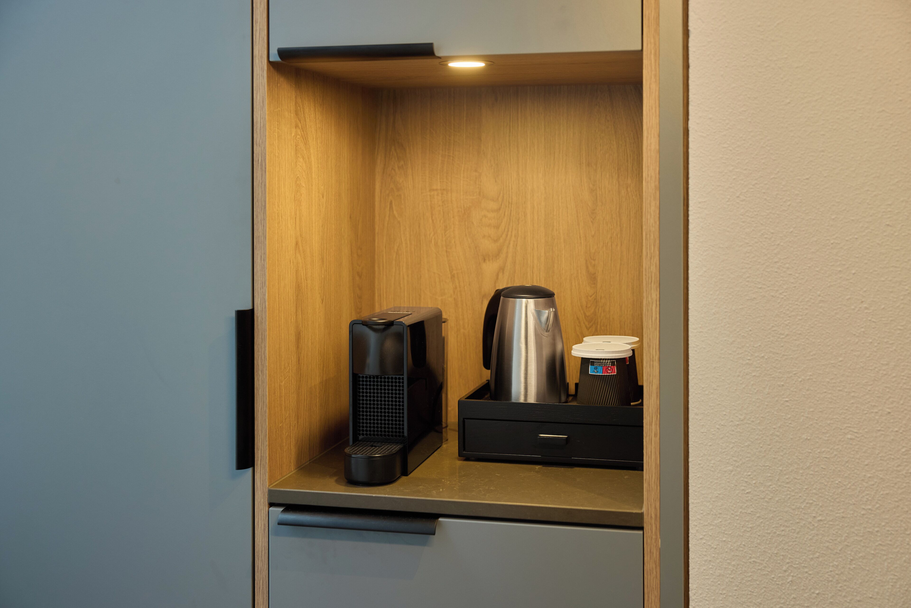 A compact kitchenette with a coffee maker, a kettle, and a small drawer.