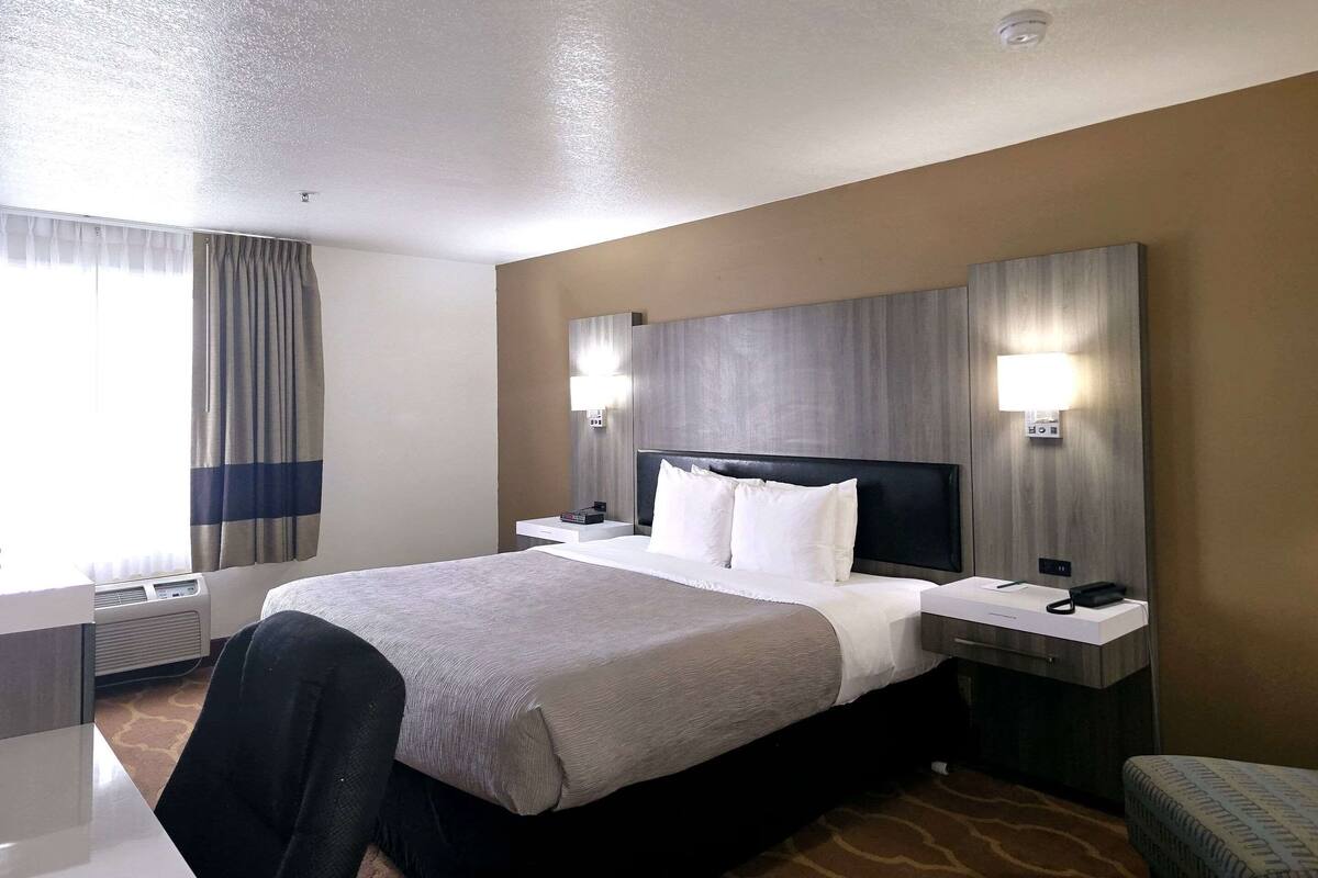 A hotel room with a large bed, bedside tables, a desk, and a chair.