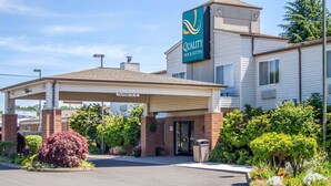 A Quality Inn & Suites with a covered entrance, brick exterior, and landscaped garden area. - Quality Inn & Suites Longview Kelso (Longview)