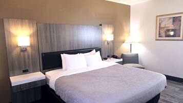 A hotel room with a large bed, two bedside tables, a chair, and a painting on the wall.