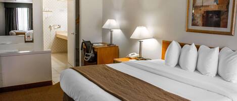 A hotel room with a large bed, two bedside lamps, a desk with a telephone, and a painting on the wall.