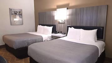 Ein Hotelzimmer mit zwei Betten, einem Nachttisch mit Lampe, einem Telefon und einem Bild an der Wand.