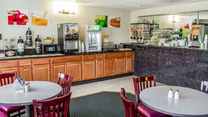 A restaurant with wooden cabinets, a counter with food display, and a seating area with tables and chairs. - Quality Inn & Suites Longview Kelso (Longview)
