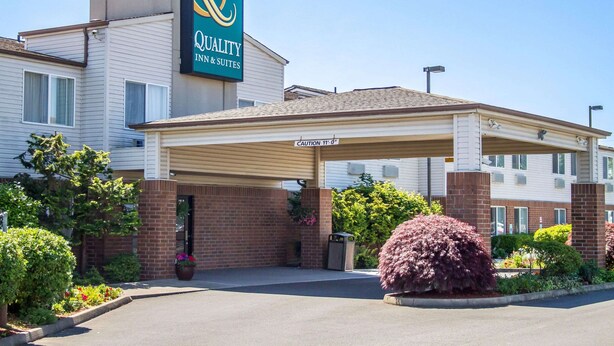 A hotel with a covered entrance, a sign for 'Quality Inn & Suites', and a 'CAUTION 11-0' sign.