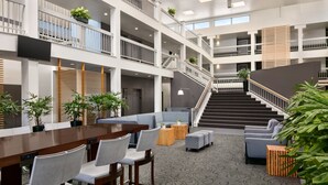 A spacious lobby with a central seating area, multiple levels with balconies, and a staircase leading to upper floors. - The Domain Hotel (Sunnyvale)