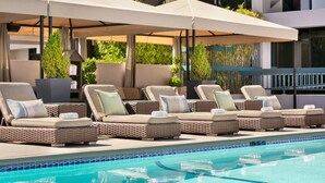A poolside area with lounge chairs and umbrellas. - The Domain Hotel (Sunnyvale)