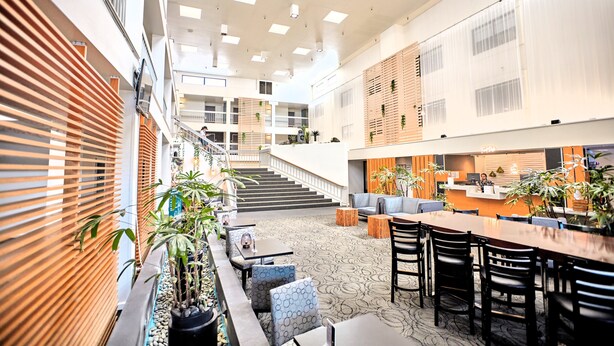 A spacious indoor area with a central staircase, seating arrangements, and a reception desk. - The Domain Hotel (Sunnyvale)