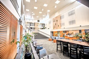 Zona interior espaiosa amb una escala central, zones d'estar i una taquilla de recepció.