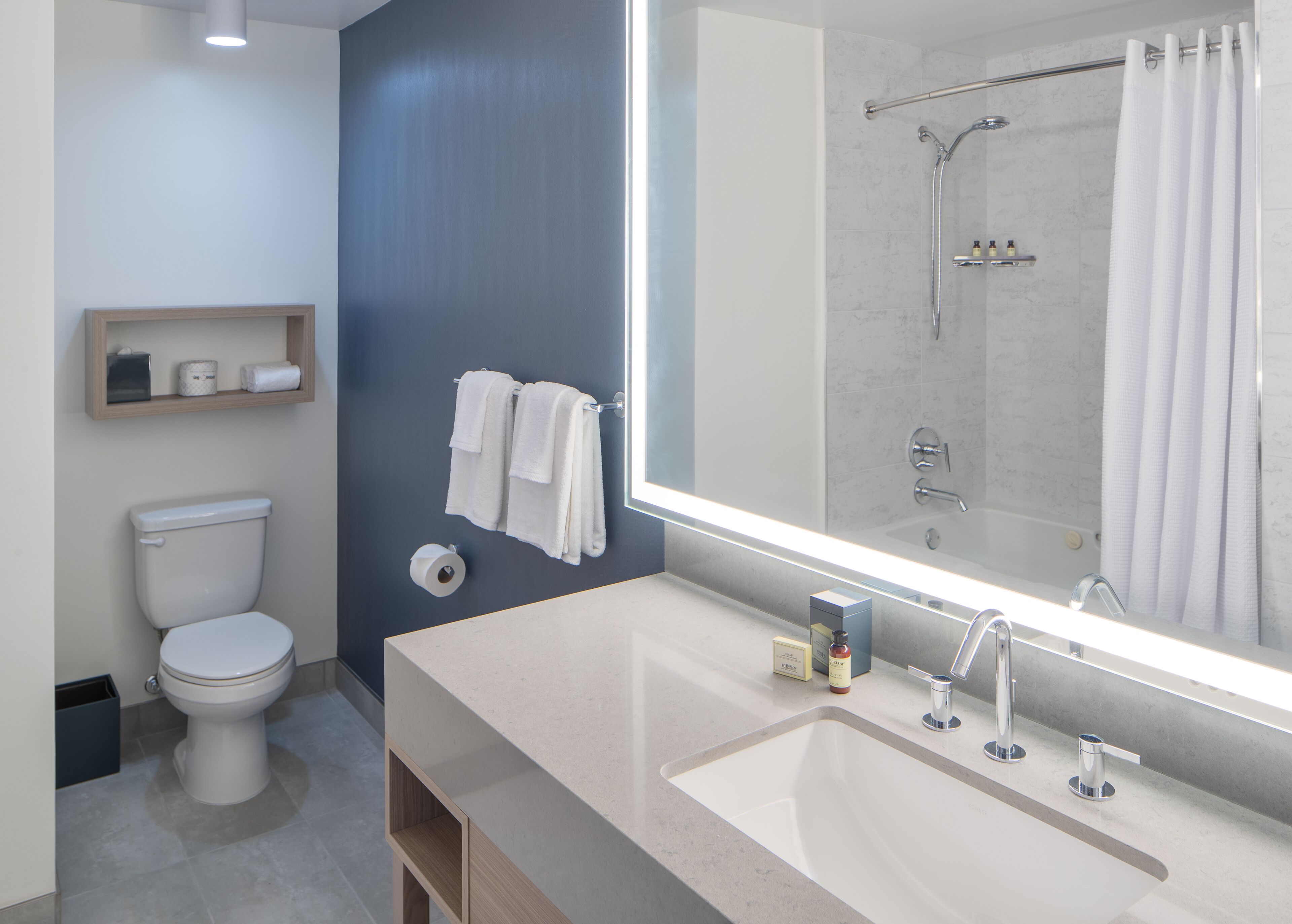 A modern bathroom with a toilet, a sink, a mirror, and a shower.