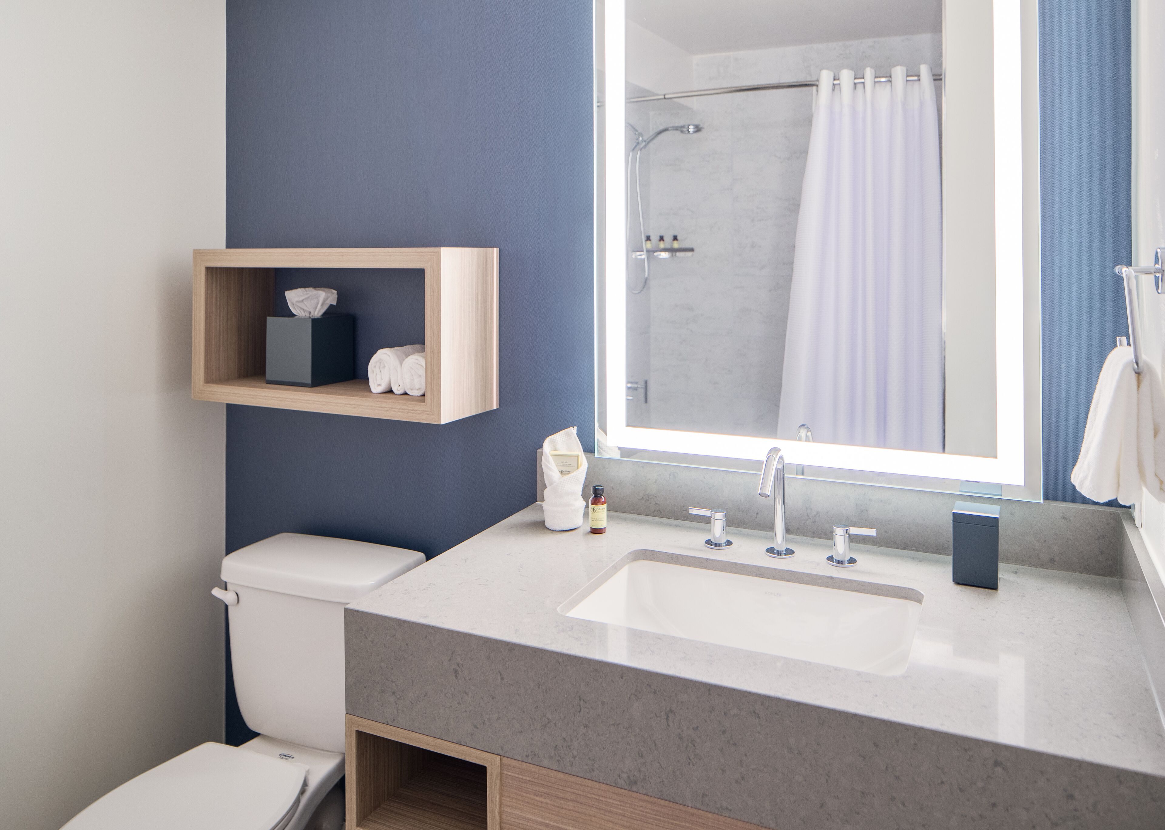 Un baño moderno con un espejo grande, un lavamanos y una ducha.