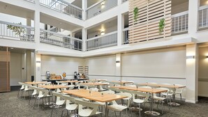 A multi-level hotel lobby with a central open space, multiple tables and chairs, and a coffee station. - The Domain Hotel (Sunnyvale)