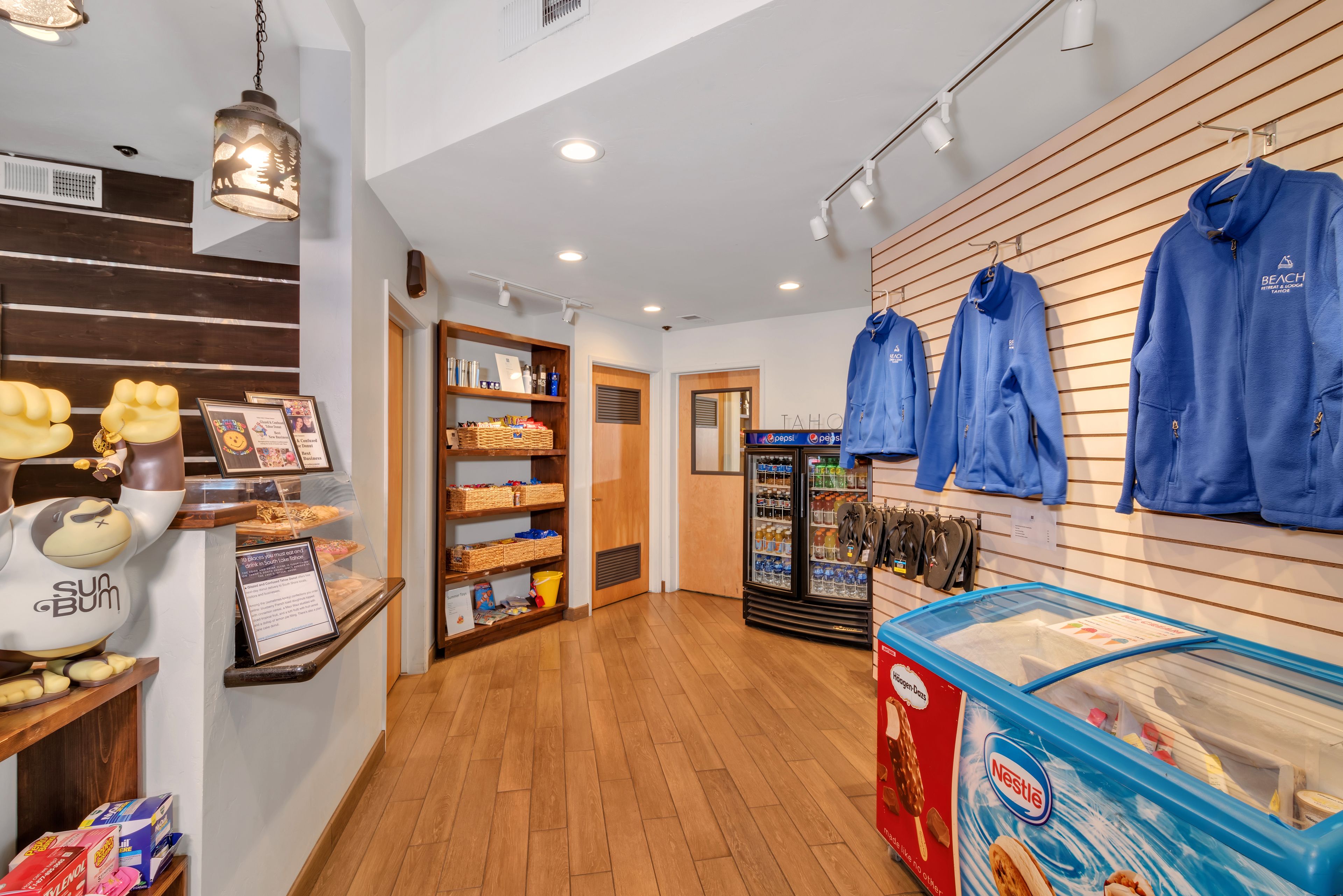 A store interior with shelves stocked with snacks, a display of blue hoodies, and a Nestle ice cream freezer.