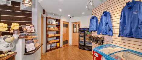 A store interior with shelves stocked with snacks, a display of blue hoodies, and a Nestle ice cream freezer.